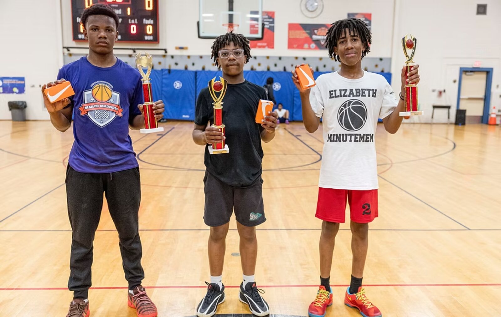 Three players holding trophies and awards after a championship game.